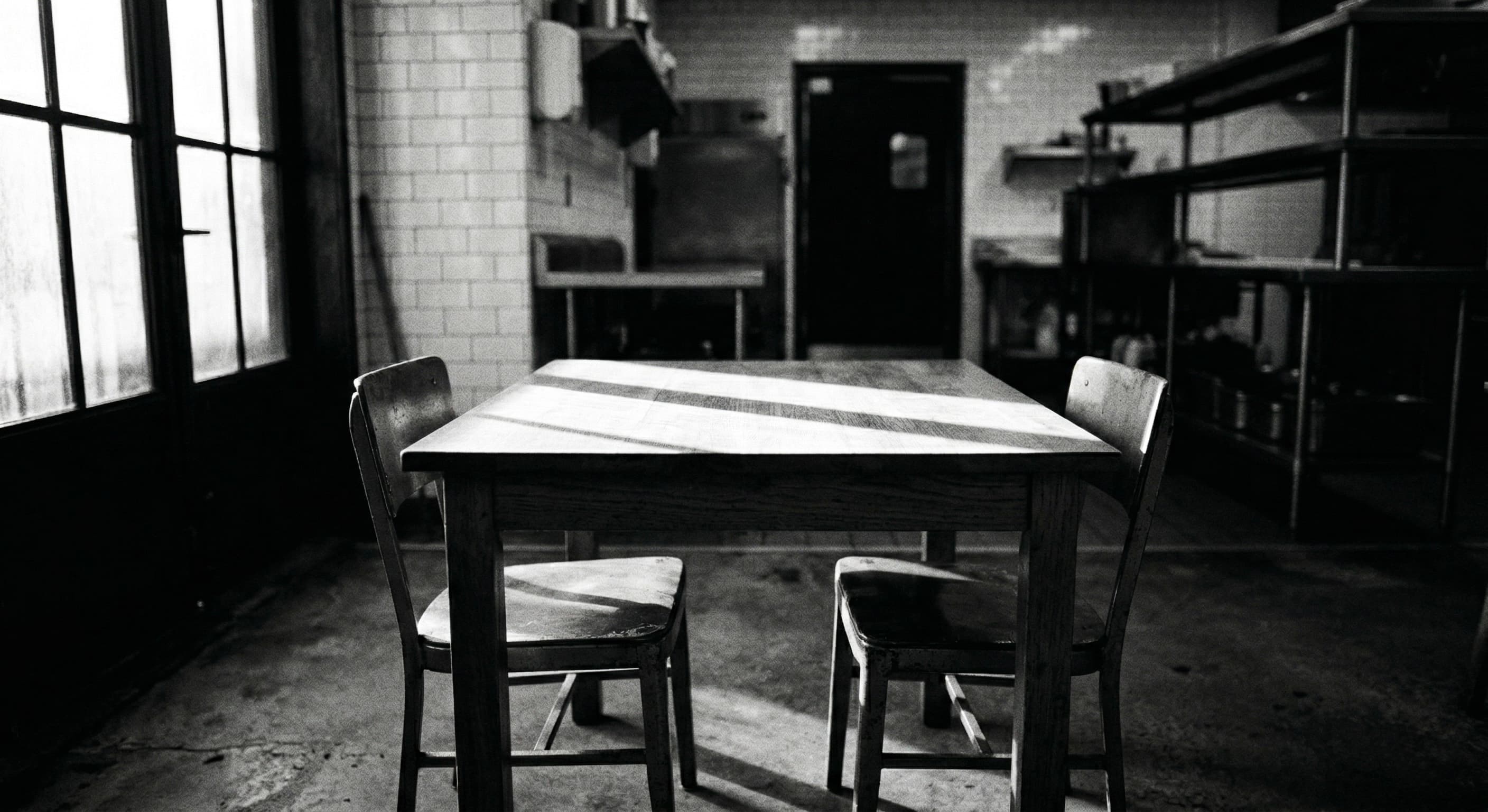 Empty table with two chairs in a restaurant kitchen — natural light from a window